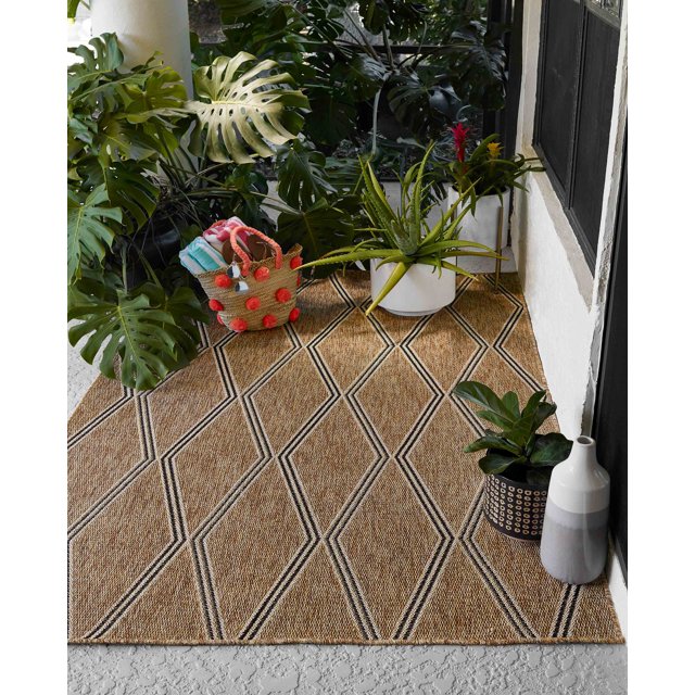 ECARPET Cypress transitional area rug featuring a beige and black geometric diamond pattern, styled on an outdoor patio floor with green plants, basket, and vases.