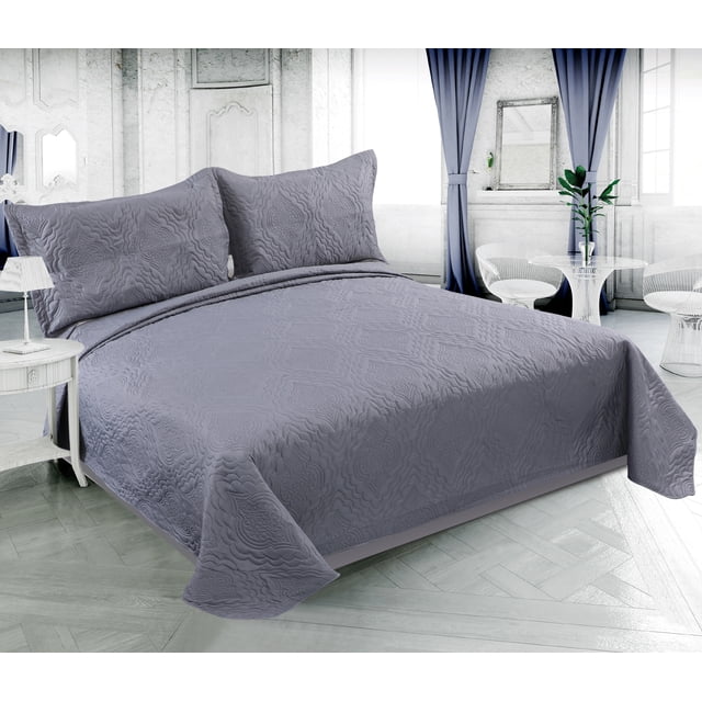 Grey solid embossed pinsonic coverlet bedspread and matching pillow shams displayed on a made-up bed in an elegant, light-filled bedroom.