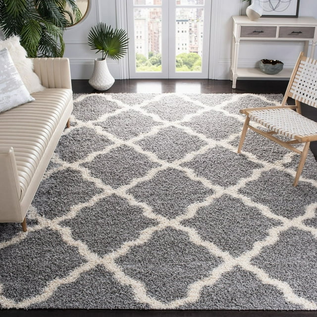 Safavieh Dallas Logan gray shag area rug featuring a white geometric diamond pattern, styled in a contemporary living room with beige sofa and wooden chair.
