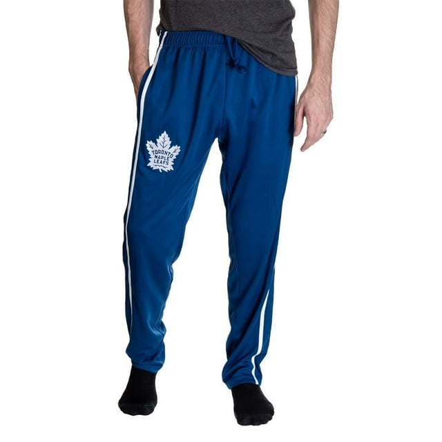 Maple Leafs de Toronto Pantalon d'Entraînement à Rayures pour Hommes en Bleu, avec Deux Rayures Latérales Blanches, un logo d'Équipe Brodé sur la Cuisse Gauche et une Taille à Cordon Ajustable. Fabriqué en polyester 100 %, Ce Pantalon sous Licence Officielle LNH Comprend Deux Poches Latérales et des Bas à Jambe Ouverte pour le Confort et la Fonctionnalité.