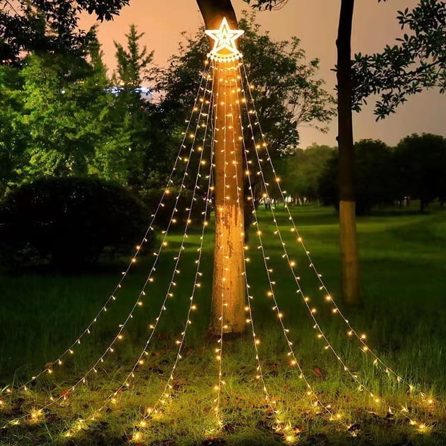 luces de estrellas yongsheng 320 led cadena de cortina blanca cálida para exteriores, a menudo usadas como decoración navideña; vista frontal de tiras LED en cascada con una estrella iluminada en la cima, colocadas alrededor de un tronco en césped nocturno para iluminación ambiental exterior.