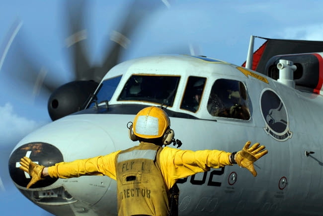 A Flight Deck Director Signals The Pilot Of An E 2C Hawkeye To Spread 