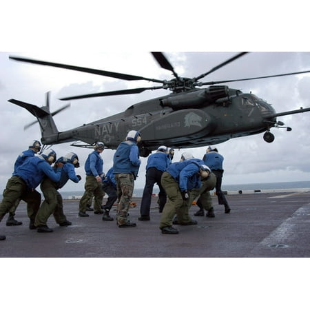 Crew members brace themselves as an MH-53E Sea Dragon lands on the ship's flight deck Poster Print by Stocktrek Images (