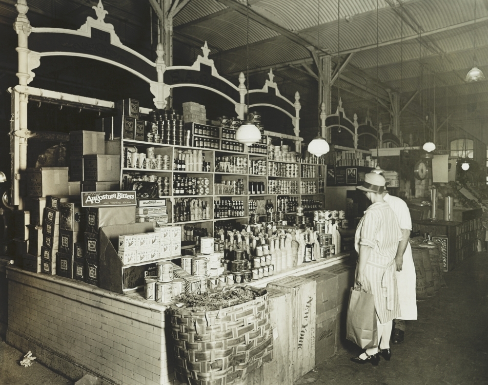 Woman Shopping For Canned Goods At Grocery Store In The 1920S. The OldFashioned Store Has Many