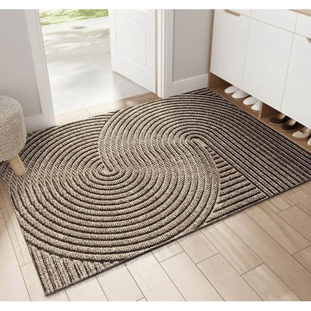 felpudos de entrada resistentes al desgaste: felpudos antideslizantes para uso doméstico, que eliminan la arena y el polvo Tapete rectangular 45x75 cm en color caqui, vista 3/4; superficie de bucle con diseño en espiral y franjas que retienen polvo y arena, borde cosido y base antideslizante de PVC, colocado frente a una puerta sobre piso de madera; también adecuado para vestíbulos y zonas de zapatos.