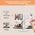thumbnail image 3 of Rotating acrylic display features MUSIC letters with a guitarist on stage surrounded by musical notes and accessories in a vibrant composition, 3 of 7