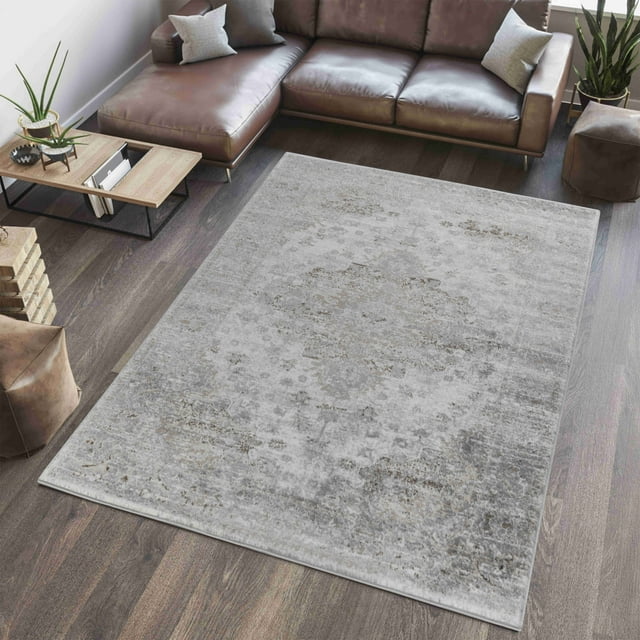 Rug Branch Sakarya Collection Oriental distressed indoor area rug in muted gray tones placed on wood flooring under a brown leather sectional sofa.