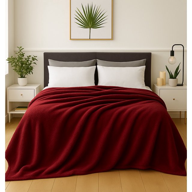frazada cobija súper suave premium | cobertor liso | soft nature color Vino tamaño Matrimonial 180 cm x 220 cm. Vista frontal centrada de cama con cobertor liso vino en microfibra 100%; pliegues visibles que muestran textura afelpada, cabecera oscura y almohadas blancas, burós con planta y lámpara como contexto. Suele usarse también como capa adicional en sofá o sala.