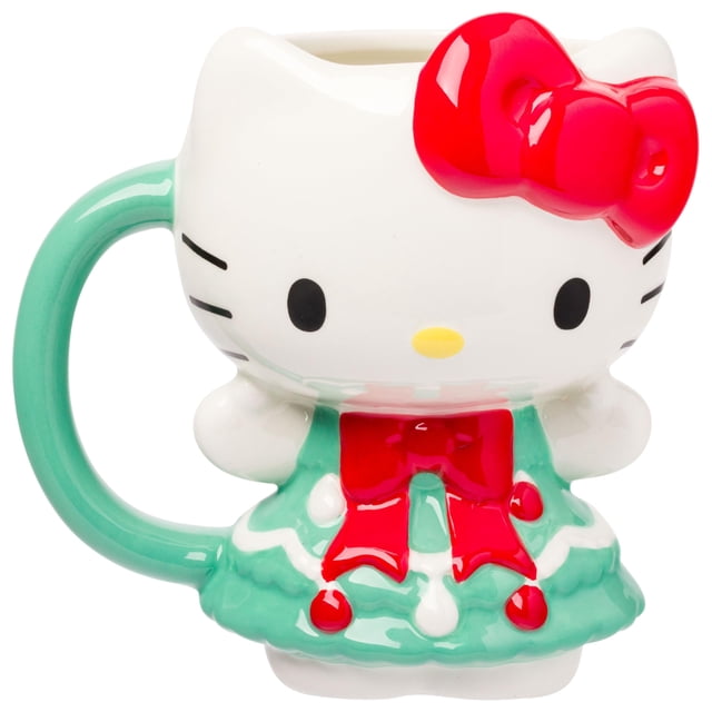 taza de cerámica Silver Buffalo Sanrio Hello Kitty 600 ml Christmas Vista 3/4 de una taza blanca esculpida en 3D con la cabeza de Hello Kitty, asa verde menta y lazo rojo brillante; vestido en forma de árbol de Navidad verde con detalles rojos y blancos. Ideal para té o café de mañana y también usada como organizador de bolígrafos; lavar a mano.