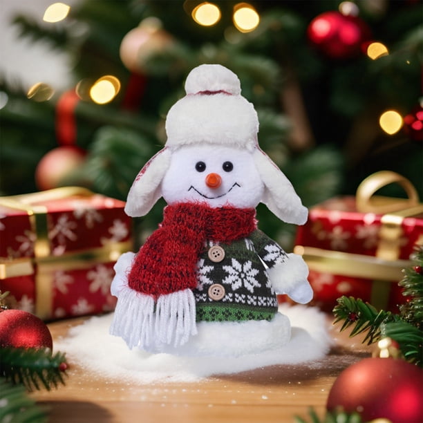 Bonita figura de muñeco de nieve sentado de Navidad que muestra una muñeca en la ventana.