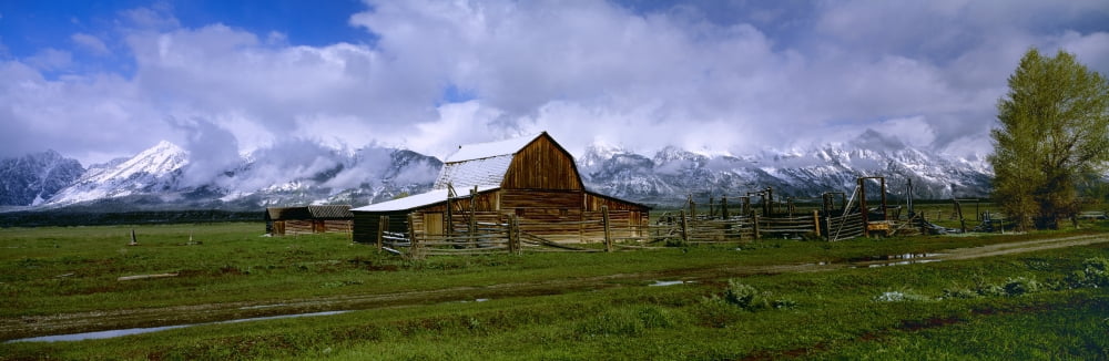 Agriculture - Historic wooden barn an outbuilding and corrals partially covered in Spring snow with the Grand Teton Mountains in the background Teton County Wyoming USA Canvas Art - Charles Blakeslee