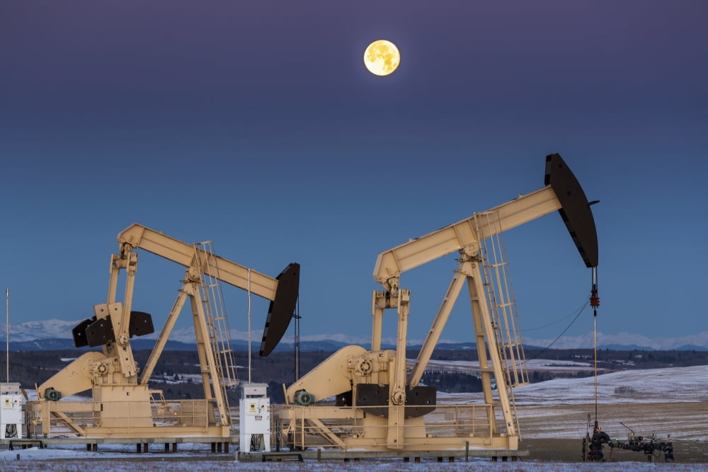 Two pump jacks at dusk in a snow covered field with a full moon in a clear sky and snow covered foothills and mountains in the background Alberta Canada Canvas Art - Michael Interisano Design Pics (3