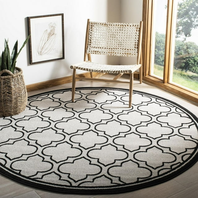 Safavieh Amherst Wilson round area rug featuring black geometric trellis pattern on cream background in modern room setting.