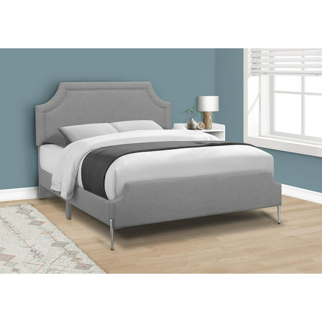 Grey queen size platform bed with upholstered linen-look frame, decorative nailhead trim on headboard, and chrome metal legs in a modern bedroom.