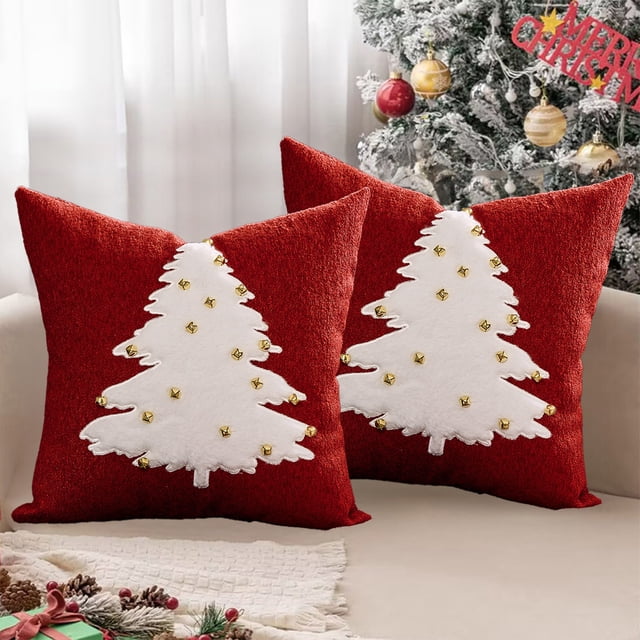 funda de almohada navideña de 45 x 45 cm. ideal para decoración navideña o de invierno. ideal para sofás, par de fundas cuadradas rojas 45 x 45 cm con árbol de Navidad blanco aplicado y pequeños remaches dorados, vista frontal centrada sobre sofá claro frente a árbol decorado; suelen usarse también como cojines decorativos para rincones de lectura.