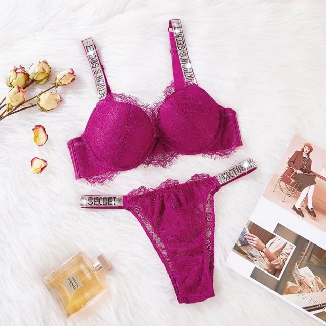 conjunto de lencería push up de encaje sexy letra caliente 2 piezas bragas w6k5 victoria secret — conjunto push-up de encaje fucsia con sujetador de copas acolchadas y aros, tirantes ajustables con cinta estampada 'SECRET' y tanga de encaje con cintura elástica estampada; colocado plano sobre fondo peludo blanco con rosas secas, frasco de perfume y revista. Consulte la tabla de tallas antes de elegir.