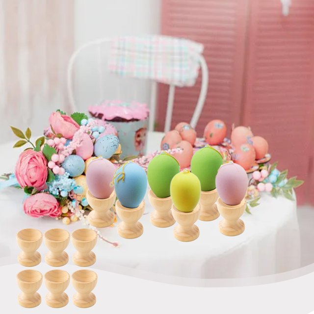fiudx porta huevos de madera, paquete de 6 en color caqui; seis portavasos de madera sin pintar con base redondeada y cuerpo cilíndrico vistos en primer plano sobre mesa con flores y huevos pintados, primer plano frontal, diseño seguro para decorar fácilmente, uso en la cocina y como regalo para celebrar Pascua.