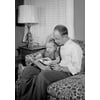 Father reading a book with his daughter sitting on his lap Poster Print