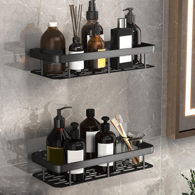 estante organizador de baño macarena aluminio fuerte doble capa negro montado en pared, vista frontal 3/4 con dos repisas rectangulares de aluminio perforado para drenaje y barra frontal sólida; sostiene botellas de champú, gel y accesorios sobre azulejo gris, placas adhesivas de montaje visibles, tamaño aprox. 30 x 13 x 5 cm. Suele usarse también para ordenar artículos pequeños en cocina o lavandería.