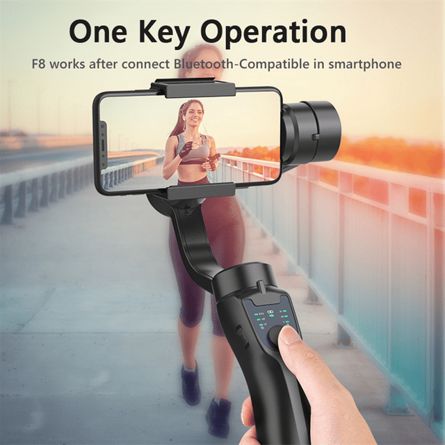 F8 Handheld 3-Axis Gimbal Stabilizer Phone Holder in black, designed for smartphones up to 7 inches. The stabilizer features a 320° panoramic rotation, Bluetooth connectivity, and a single-click photo or video capture function. A hand is shown operating the gimbal, holding a smartphone displaying a video recording of a person jogging on a bridge. The gimbal includes a tripod and USB cable, with a working time of 4-6 hours and a 2200mAh battery capacity.