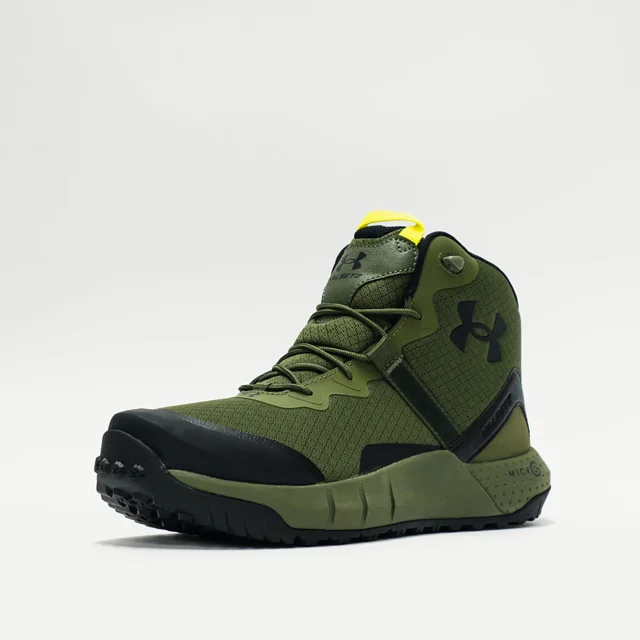 tenis deportivos under armour micro g valsetz 27 cm Tenis deportivos Under Armour color verde, vista 3/4 frontal; bota de caña media con cordones elásticos y lengüeta acolchada, logo negro lateral y refuerzos negros en puntera y talón. Corte de material resistente con patrón cuadriculado, entresuela Micro G® de amortiguación y suela de goma de alta resistencia a la abrasión con dibujo de tracción. Recomendado para campismo; también suele usarse como calzado táctico ligero para caminatas cortas.