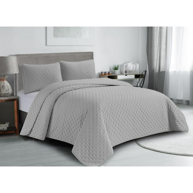 Lightweight, hypoallergenic gray pinsonic quilt set with matching pillow shams displayed on a bed in a bright, minimalist bedroom.