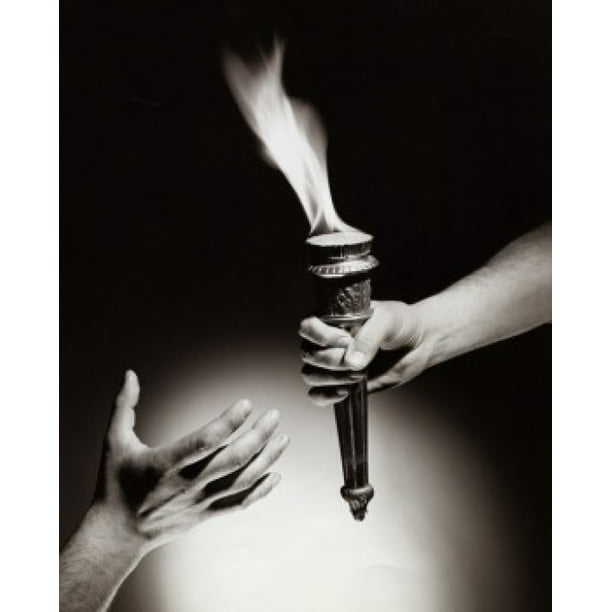 Closeup of a person's hand passing a flaming torch to another person