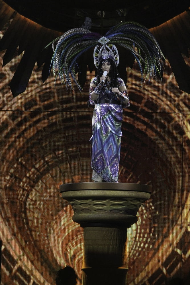 Cher wearing a feather headdress performing in the Dressed To Kill tour