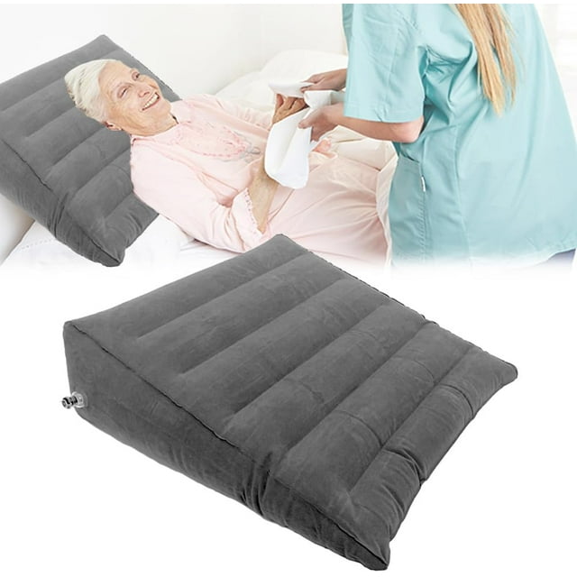 GHSDFBB Inflatable Orthopedic Bed Wedge Pillow designed for travel, sleeping, and backrest support. Made of PVC flocking in a dark grey color, it provides an incline for improved circulation, reduced swelling, and relief from acid reflux. Suitable for bedridden, disabled, elderly, and patients with arthritis or snoring issues. Lightweight, foldable, and compact for easy storage and travel. Shown in use on a bed with a caregiver assisting.