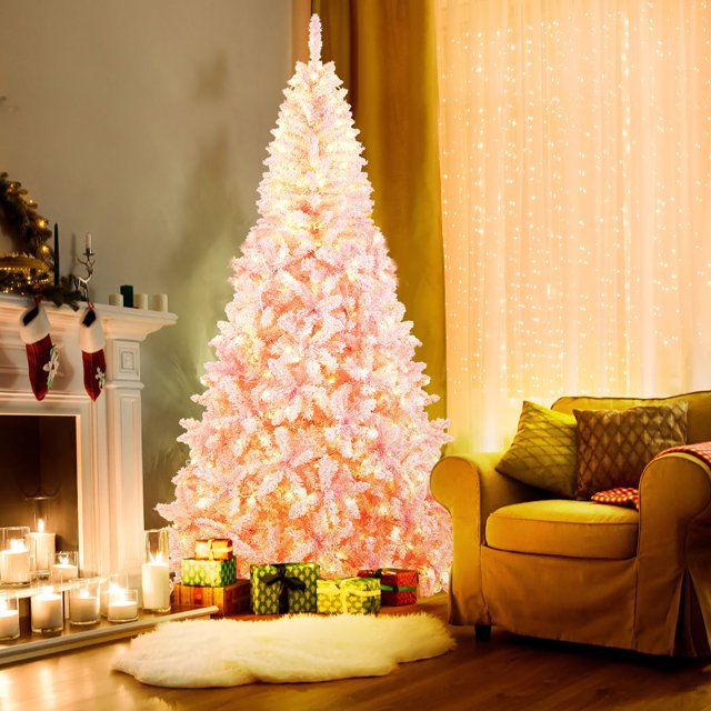 Gymax 7.5FT Pre-Lit Hinged Artificial Snow Christmas Tree in pink with 450 warm white LED lights and 1100 flocked PVC branch tips. The tree features 8 lighting modes, a hinged structure for easy setup, and a sturdy folding metal stand. Displayed in a cozy living room with wrapped gifts and festive decor.