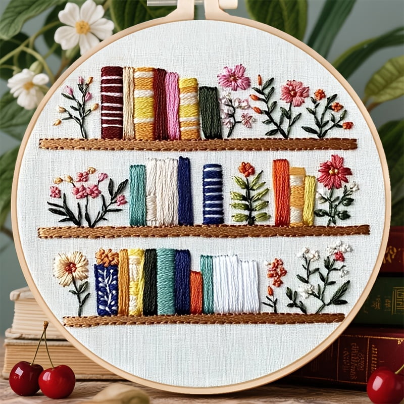 An Embroidery Kit Featuring a Bookshelf Floral Pattern Measuring, Suitable for Both Adults And Beginners. It Includes Instructions, Printed Fabric, an Embroidery Hoop, And Needle And Thread