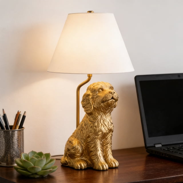 NWOKYZGH Decor Collection Lighting Golden Doodle Table Lamp with gold finish and tapered linen shade. Features a detailed golden doodle-shaped base with a gold finish, paired with a white tapered linen shade. Dimensions include a 10-inch diameter base and an overall height of 18 inches. Includes a 5-foot clear power cord and supports an A19 E26 60-watt bulb (not included). Displayed on a wooden desk alongside a laptop, a succulent plant, and a pencil holder.
