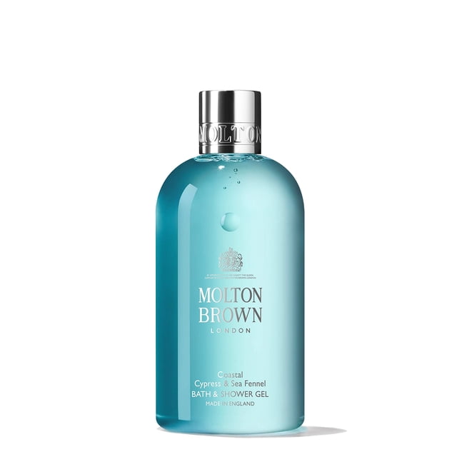 molton brown bath & shower gel, coastal cypress & sea fennel, 10 oz. Vista frontal de botella transparente azul mar de 10 oz con tapa plateada; etiqueta con logo Molton Brown y texto 'Coastal Cypress & Sea Fennel BATH & SHOWER GEL', acabado brillante y pequeña burbuja en el hombro. Indicado para duchas energizantes y uso diario; también apto para llevar en bolsa de gimnasio.