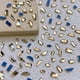 thumbnail image 1 of Juego de 150 diamantes de imitación de cristal para uñas, diamantes de imitación 3D de múltiples formas con fondo plano, para decoración de uñas, manualidades, teléfonos, ropa, joyas, bolsos, 1 of 6