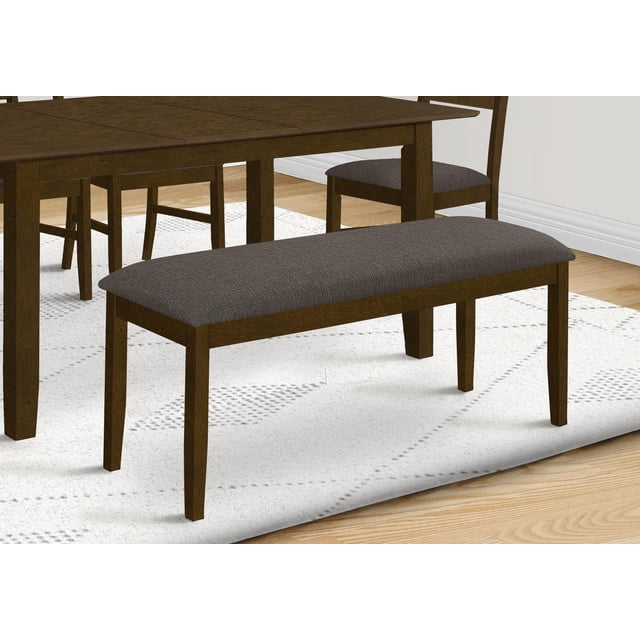 44-inch Monarch Specialties rectangular bench with brown solid wood frame and brown upholstered fabric seat, shown in dining room setting on white patterned rug.