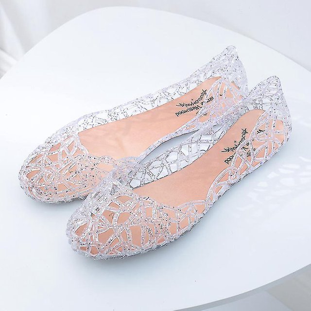 sandalias de gelatina de playa de verano para mujer, zapatos planos sin cordones, informales, transpirables — par de sandalias planas transparentes de plástico con calado geométrico y plantilla rosa visible, tacón bajo de 1 cm; vista 3/4 frontal sobre fondo blanco, pensadas para uso diario y playa y también adecuadas como calzado ligero para viajes cortos.