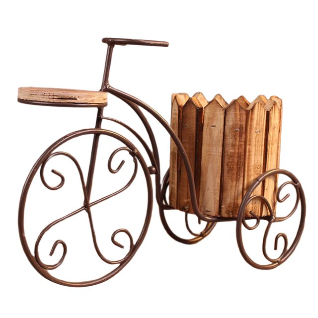maceta de hierro para bicicleta de estilo parisino, soporte para plantas en hierro forjado con cesta en color madera, vista 3/4 frontal que muestra manillar y marco tubular curvado, ruedas decorativas con espirales y cesta de listones para maceta de 31x12x16 cm; ideal para porche, balcón o decoración interior; también suele usarse como soporte decorativo para macetas pequeñas.