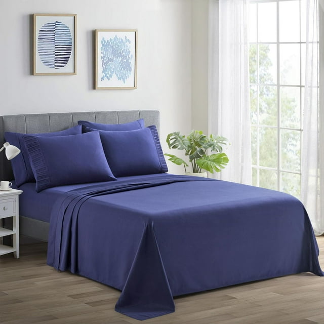 Navy blue Marina Decoration ultra soft silky rayon from bamboo deep pocket sheet set with matching pillowcases displayed on a gray upholstered bed in a sunlit room.