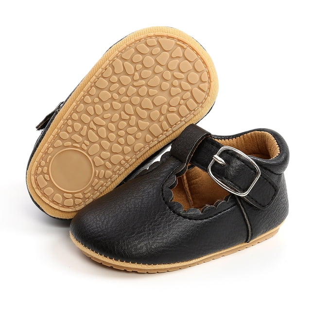 zapatos de bebé suela de goma suave sandalias de cuero flexibles para bebés antideslizantes para exteriores, sandalia negra de cuero sintético con cierre de gancho y hebilla y borde festoneado; suela de goma clara con patrón antideslizante y plantilla acolchada, vista frontal con otra sandalia mostrando la suela sobre fondo blanco; también adecuada para sesiones de fotografía de recién nacido.
