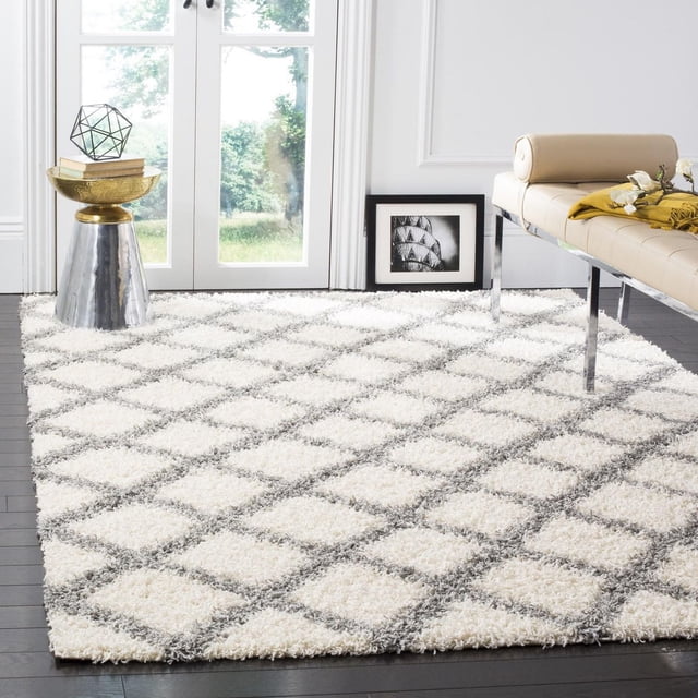 Safavieh Dallas Jerrie white shag area rug featuring a gray geometric diamond pattern on dark hardwood floor in a bright, modern living room setting.