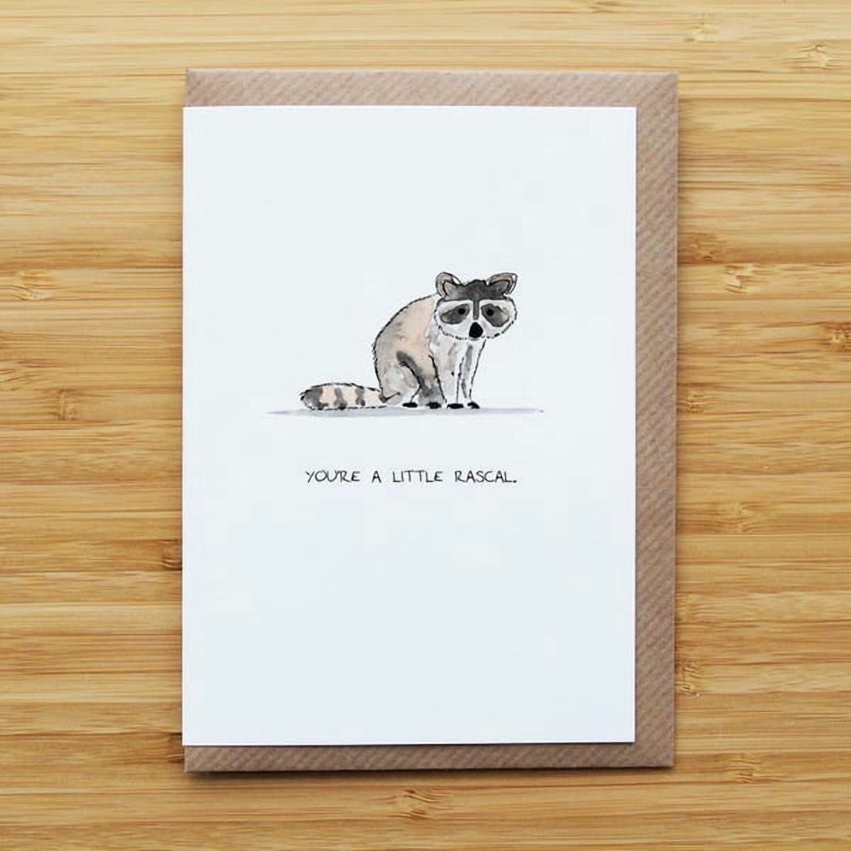 Whimsical raccoon card "You're a little rascal" suitable for kids or friends, playful illustration for various cheerful occasions.