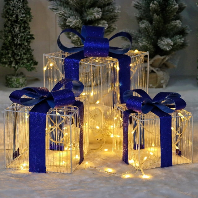 christmas blue bow decorative gift box 3 piece set glowing light christmas tree decoration ornaments accessories for mall hotel window display conjunto de tres cajas de regalo azul con lazo, vista en 3/4, estructura metálica translúcida con tiras de LED blanco cálido en el interior y lazos azul brillante arriba; tamaños 14 cm, 16 cm y 19 cm mostrados juntos sobre superficie con luces dispersas, ideal para decorar árbol de Navidad, vitrinas o exhibiciones en hotel y comercio.