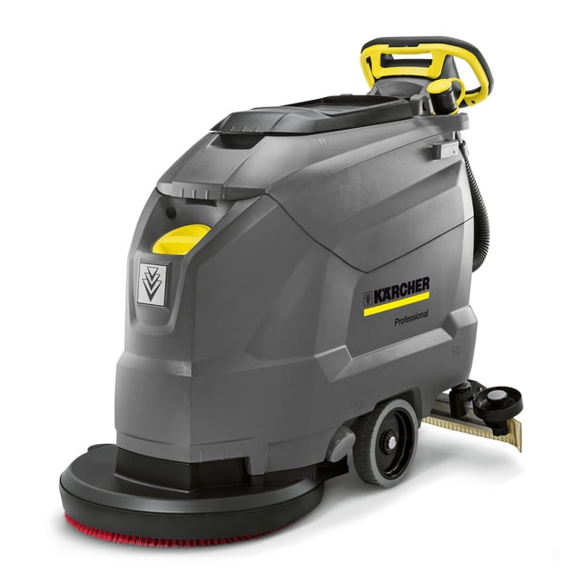 fregadora pulidora de pisos con aspirado karcher bd 50/60 c gris Karcher — vista 3/4 frontal de la máquina profesional con carcasa gris, base redonda con cepillo visible, asas amarillas, ruedas traseras y manguera lateral; suele emplearse para limpieza y abrillantado de suelos duros en entornos comerciales.