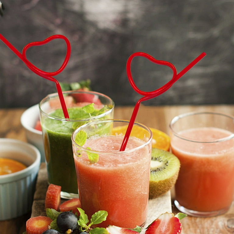 heart shaped straw and giant cocktail glass/Giant cocktail Glass with 2  heart-shaped straws and black background Concept of Valentine's day drink.  Stock Photo
