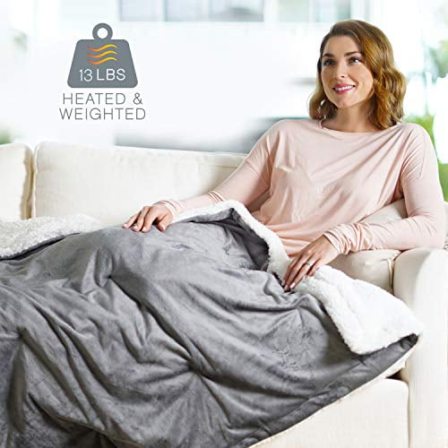 Pure Enrichment WeightedWarmth 2-in-1 Original Heated Weighted Blanket in grey, measuring 50 x 60 inches and weighing 13 lbs. The blanket features a soft micromink front and sherpa back, offering 4 heat settings ranging from 90°F to 105°F. It is designed with BPA-free, non-toxic glass beads for even weight distribution and deep pressure stimulation. The image shows the blanket draped over a person seated on a couch in a cozy indoor setting.