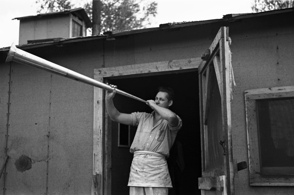 Minnesota Lumber Camp. /Ncamp Cook Blowing Dinner Horn, At A Lumber
