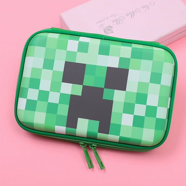 minecraft-estuche, estuche grande 2 compartimentos lleno de material escolar, minecraft-regalos estuche grande con diseño pixelado de Creeper en tonos verdes, vista frontal rectangular con doble cremallera visible y costuras reforzadas, superficie semimate y borde verde, sobre fondo rosa; también adecuado como estuche de viaje para útiles escolares.