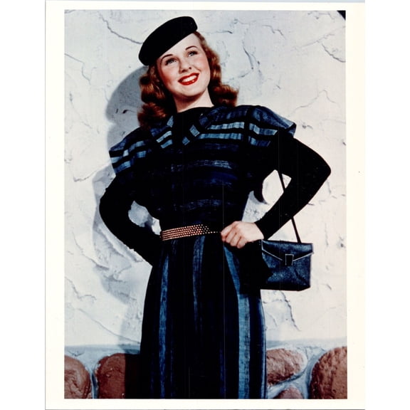 Deanna Durbin smiles as she poses with purse and hat against wall 8x10 photo