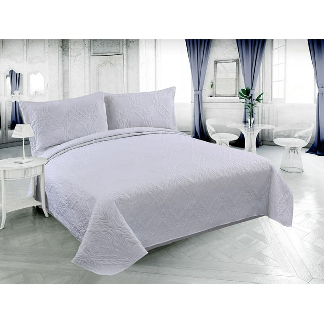 White ultra soft summer quilt set with solid embossed pinsonic design and matching shams displayed on a bed in an elegant, bright bedroom.