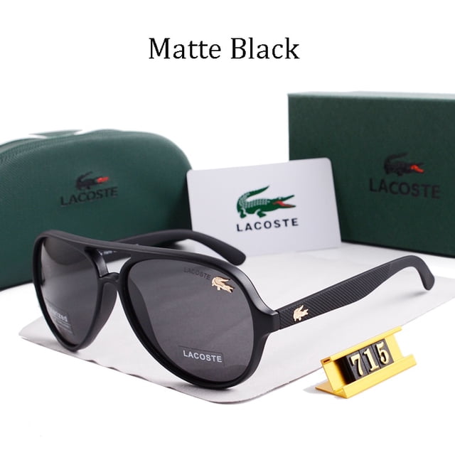 lacoste gafas de sol polarizadas estilo cuadrado fresco para hombre diseño de marca vintage gafas cuadradas con montura negra mate y lentes oscuras, logo cocodrilo dorado en patilla y frente; vista 3/4 sobre paño blanco con estuche y caja verdes de Lacoste al fondo, ideales para vacaciones y uso de viaje.